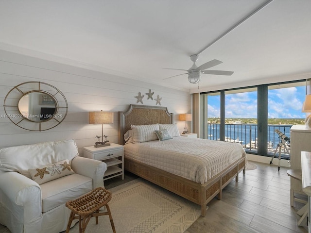 bedroom with a water view, access to outside, light wood-style flooring, and a ceiling fan