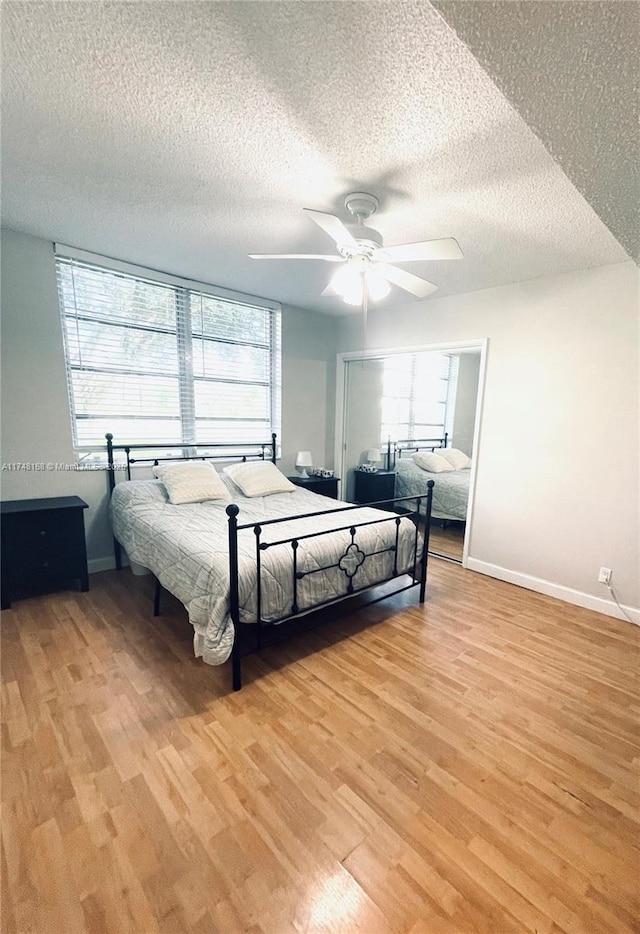 3800 Oaks Clubhouse Dr Unit 112, Pompano Beach, FL 33069 - bedroom with light wood-style floors, multiple windows, baseboards, and a textured ceiling