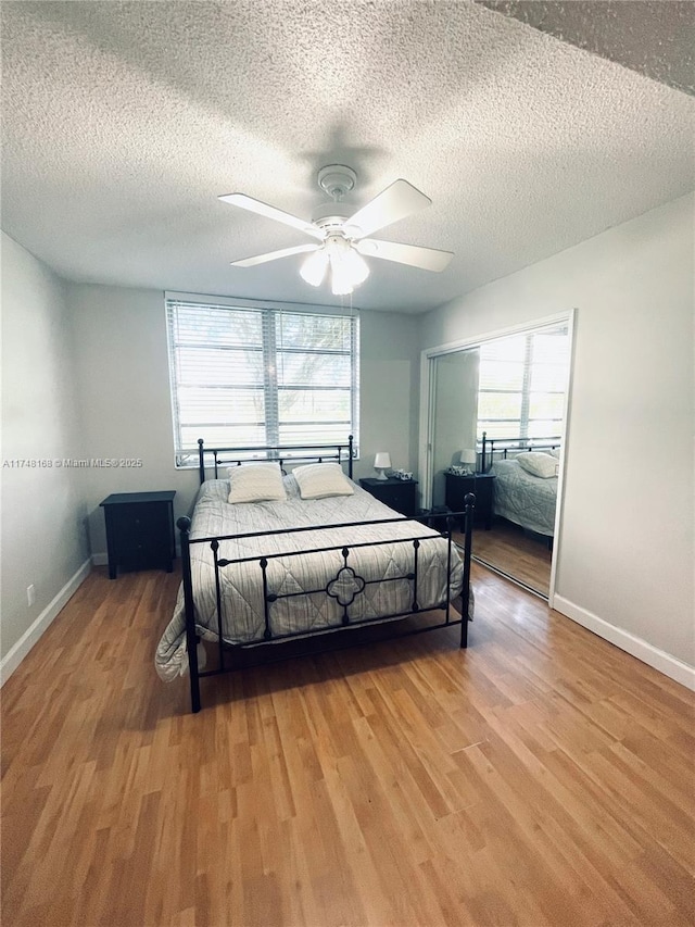 3800 Oaks Clubhouse Dr Unit 112, Pompano Beach, FL 33069 - bedroom with multiple windows, light wood-style floors, baseboards, and a textured ceiling
