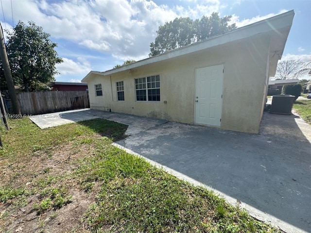 back of house with stucco siding, a yard, fence, and a patio