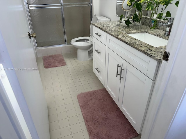 bathroom with toilet, a shower stall, vanity, and tile patterned floors