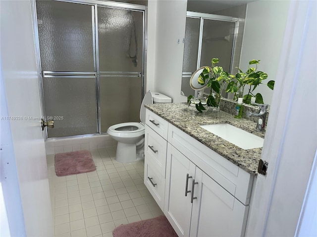 bathroom with a stall shower, vanity, toilet, and tile patterned floors