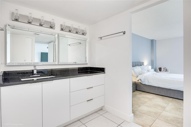 ensuite bathroom featuring connected bathroom, vanity, baseboards, and tile patterned floors