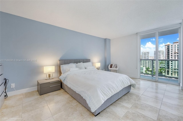 bedroom featuring a textured ceiling, expansive windows, baseboards, access to outside, and a view of city