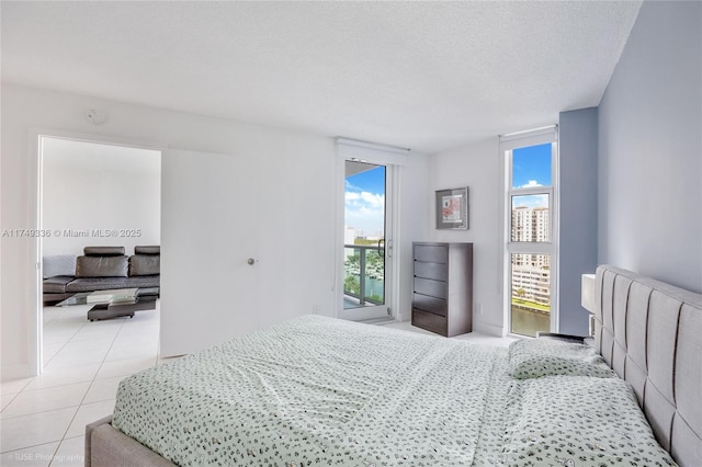 bedroom featuring access to exterior, light tile patterned flooring, and a textured ceiling