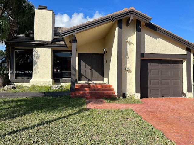 view of front facade with entry steps, a front lawn, an attached garage, and stucco siding