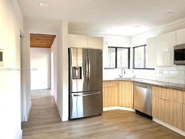 kitchen with stainless steel appliances, light wood-type flooring, stone counters, and white cabinetry