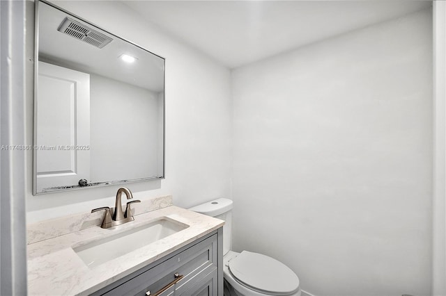 bathroom with toilet, visible vents, and vanity