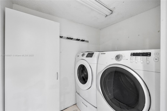 washroom featuring laundry area, a textured ceiling, and washer and dryer