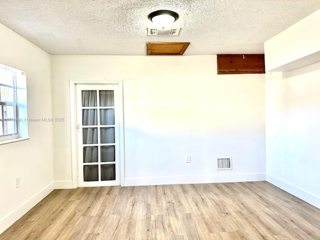 spare room with wood finished floors, a textured ceiling, and baseboards