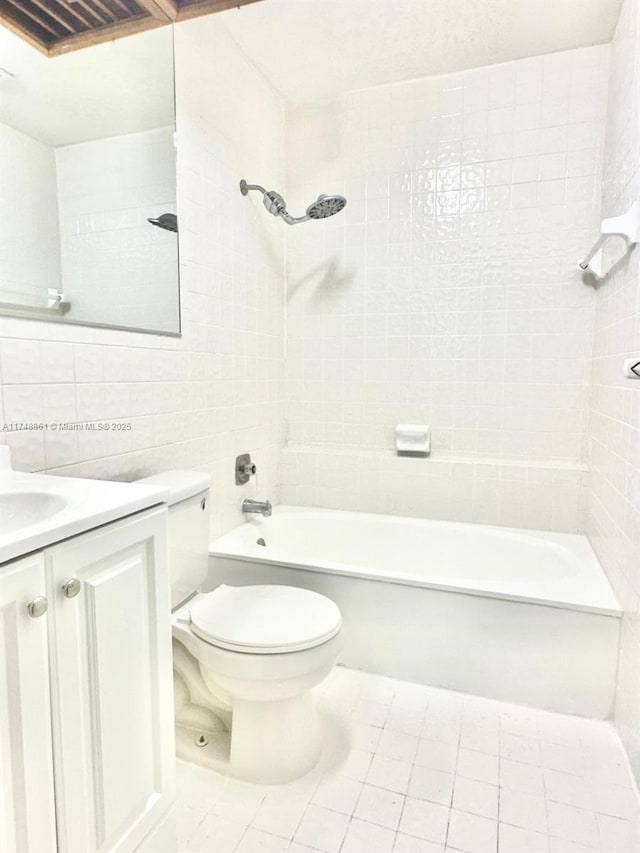 full bath featuring tile walls, toilet, tub / shower combination, vanity, and tile patterned flooring