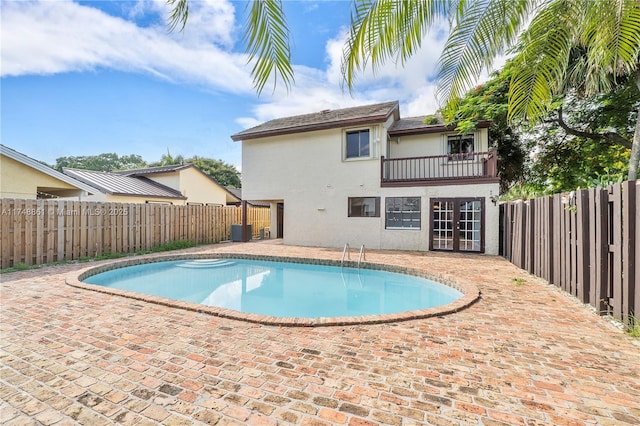 view of pool with french doors, a fenced backyard, central AC unit, and a patio area