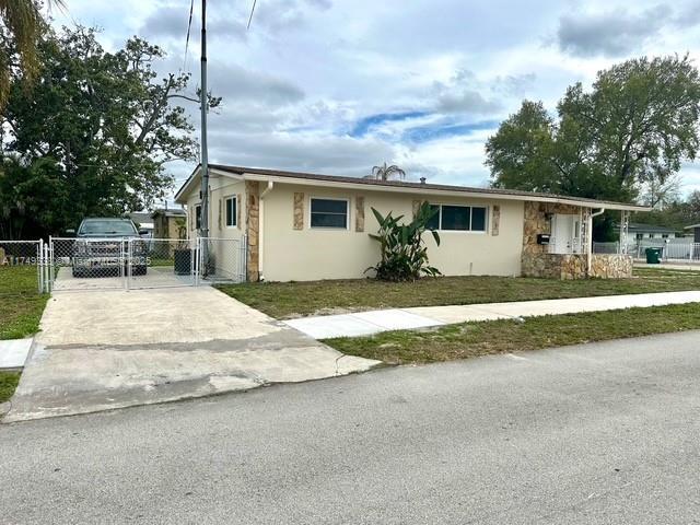 ranch-style home with a gate, fence, concrete driveway, and stucco siding