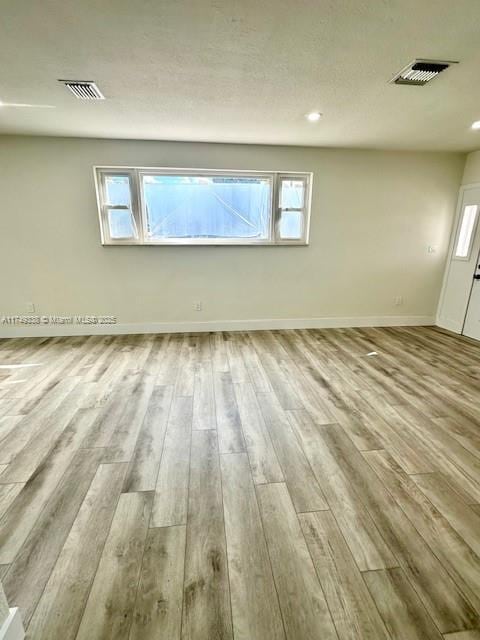 empty room featuring light wood-style flooring, visible vents, and a healthy amount of sunlight