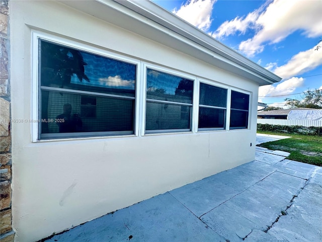 view of property exterior with a patio area, fence, and stucco siding