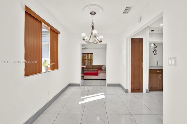 interior space featuring baseboards, marble finish floor, visible vents, and an inviting chandelier