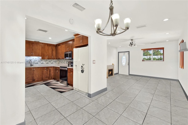 kitchen featuring pendant lighting, brown cabinets, stainless steel appliances, light countertops, and visible vents