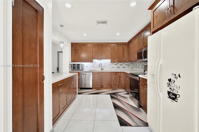 kitchen featuring visible vents, light countertops, appliances with stainless steel finishes, and decorative light fixtures