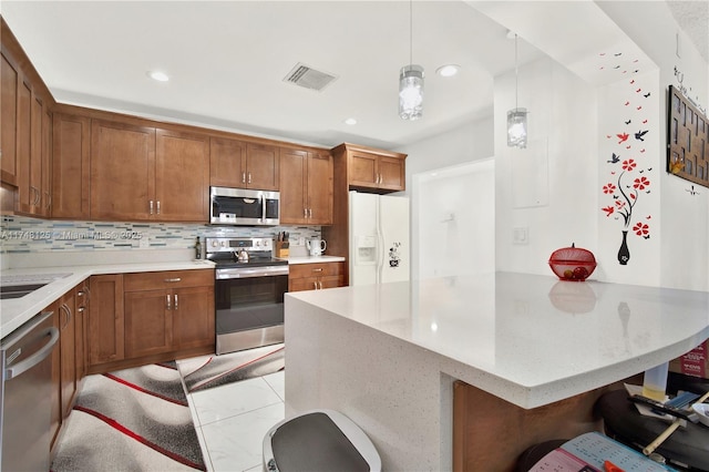 kitchen featuring tasteful backsplash, visible vents, a breakfast bar area, decorative light fixtures, and stainless steel appliances