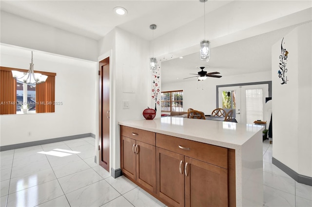 kitchen with light countertops, hanging light fixtures, brown cabinetry, and a peninsula