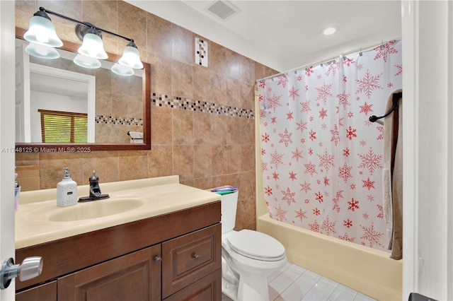 bathroom featuring visible vents, toilet, shower / bathtub combination with curtain, vanity, and tile walls