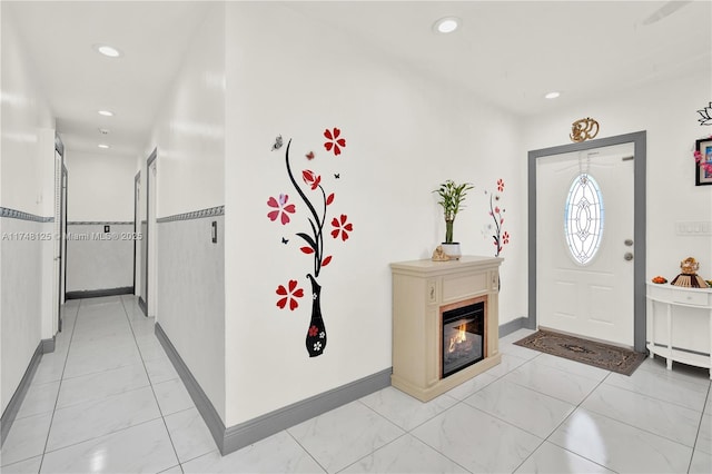 foyer with baseboards, marble finish floor, a glass covered fireplace, and recessed lighting