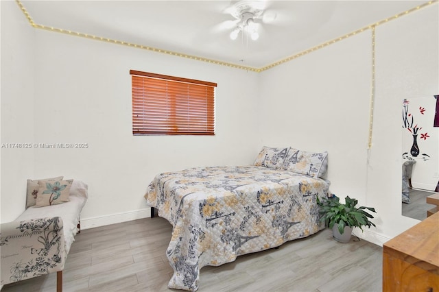 bedroom featuring a ceiling fan, baseboards, and wood finished floors