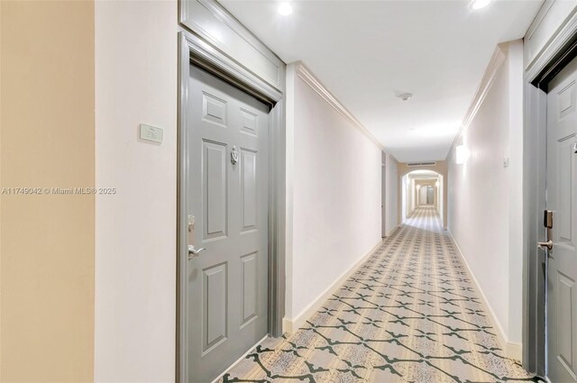 corridor featuring arched walkways, crown molding, and baseboards