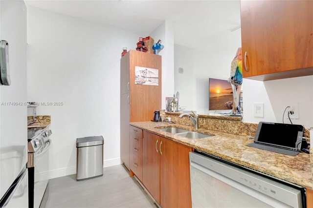 kitchen with brown cabinets, stainless steel range with electric cooktop, white dishwasher, a sink, and light stone countertops