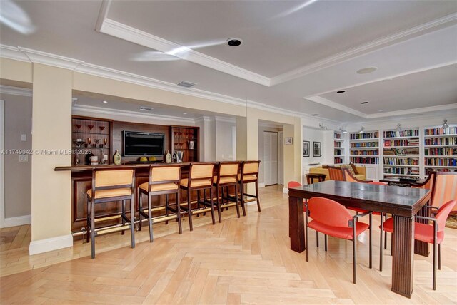 dining space with a tray ceiling, a dry bar, visible vents, ornamental molding, and baseboards