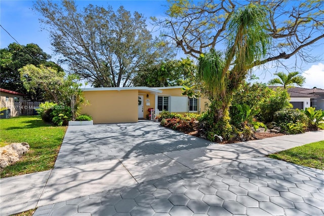 view of front facade with concrete driveway, a front lawn, and stucco siding