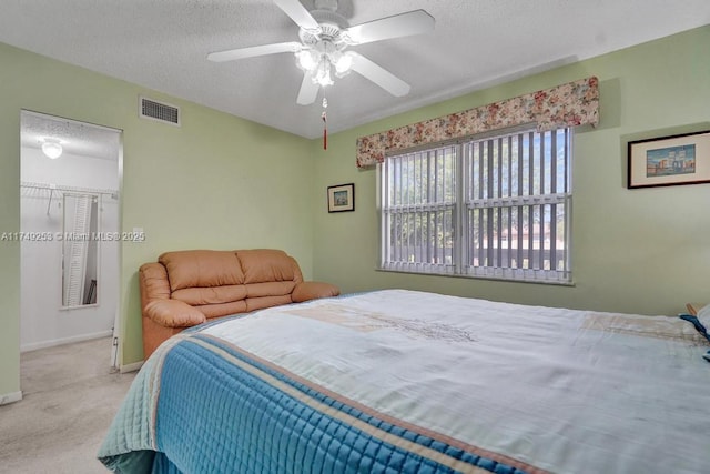 bedroom with ceiling fan, a textured ceiling, light carpet, visible vents, and baseboards