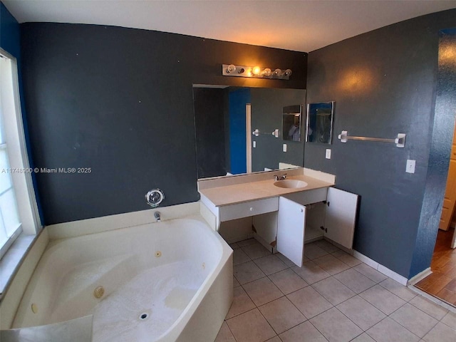 full bath featuring tile patterned flooring, a sink, a jetted tub, and baseboards