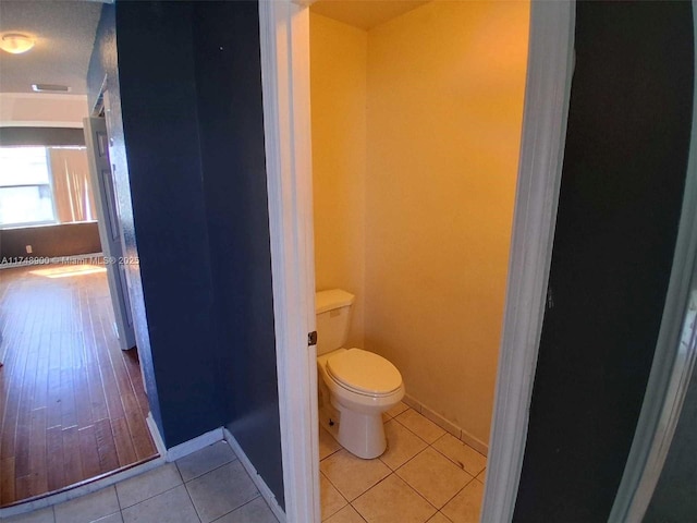 bathroom featuring tile patterned flooring, baseboards, and toilet