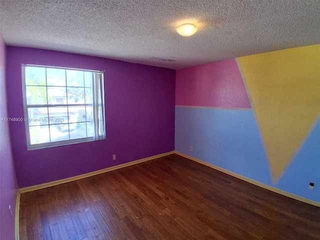 empty room featuring a textured ceiling, baseboards, and wood finished floors