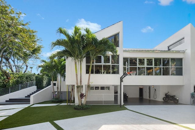 144 N Prospect Dr, Coral Gables, FL 33133 - back of house with stucco siding, stairs, concrete driveway, and a lawn