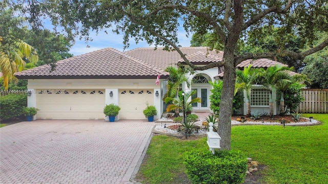 mediterranean / spanish home featuring decorative driveway, french doors, stucco siding, a tiled roof, and a front lawn