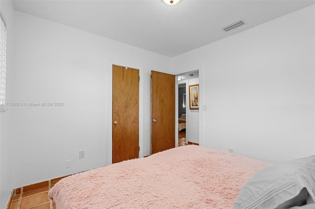 bedroom with tile patterned flooring, visible vents, and baseboards