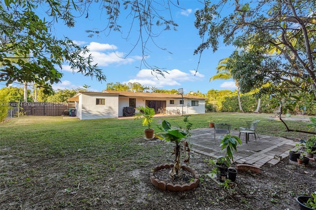 back of property with a patio, a yard, fence, and stucco siding