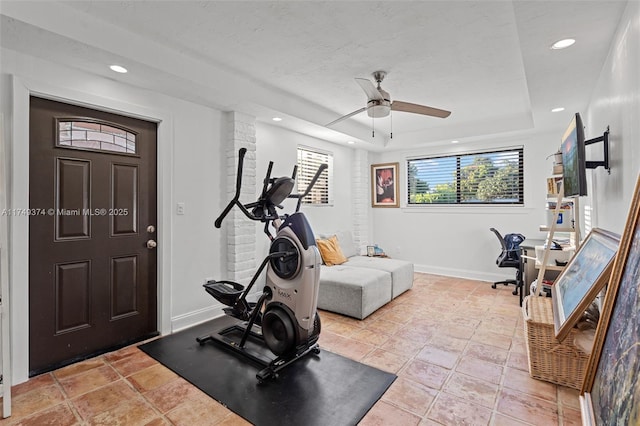 exercise room featuring ceiling fan, a textured ceiling, recessed lighting, baseboards, and a raised ceiling