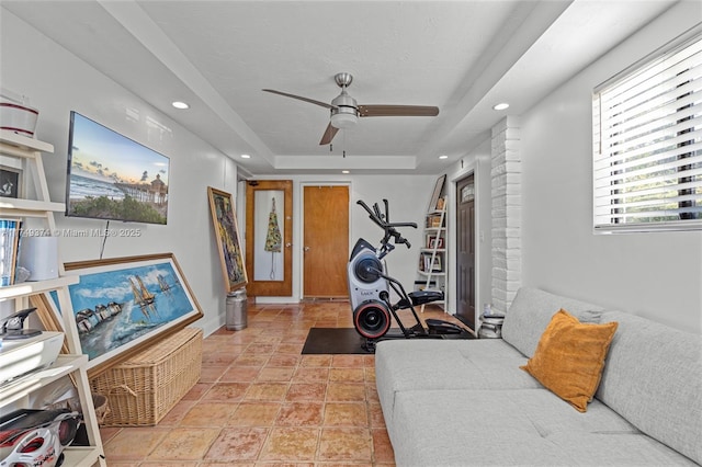 workout area featuring a raised ceiling, a ceiling fan, and recessed lighting