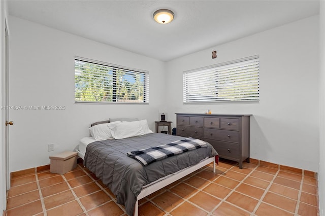 bedroom with light tile patterned floors, multiple windows, and baseboards