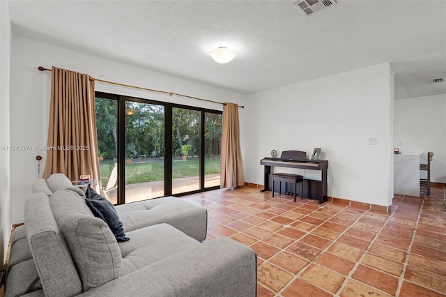 living area featuring a textured ceiling, light tile patterned floors, and visible vents