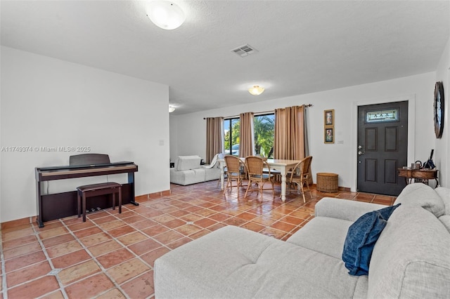 tiled living area featuring a textured ceiling, visible vents, and baseboards