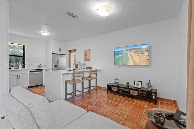 living room featuring tile patterned flooring, visible vents, and a textured ceiling