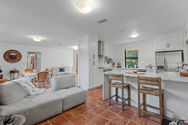 living area featuring dark tile patterned flooring, visible vents, and a textured ceiling