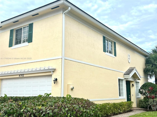 view of property exterior with an attached garage and stucco siding