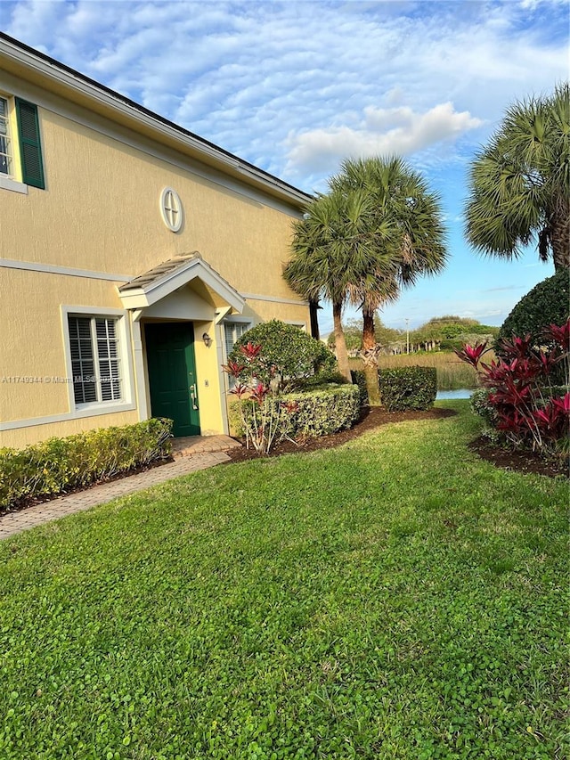 doorway to property featuring a lawn and stucco siding