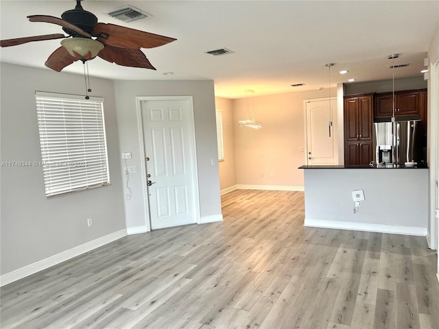 unfurnished living room with light wood-type flooring, visible vents, ceiling fan, and baseboards