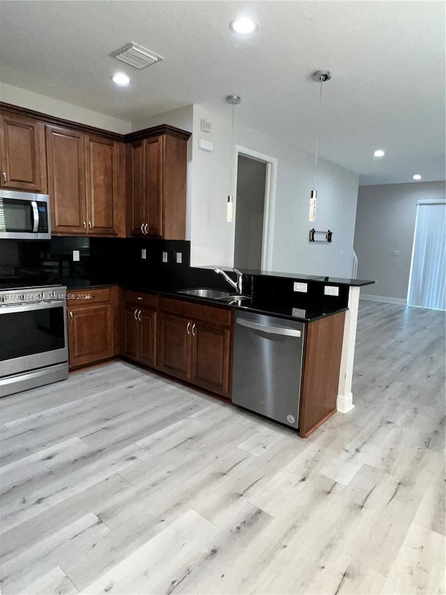 kitchen with light wood-style flooring, a sink, visible vents, appliances with stainless steel finishes, and dark countertops